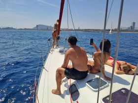 A lively group enjoys a sunny day sailing, with friends relaxing and taking photos on the deck — perfect for summer adventures on the water.