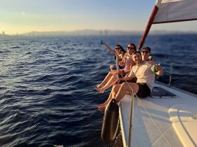 A lively group enjoys a sailing adventure, raising their drinks in celebration against a stunning ocean backdrop — perfect for unforgettable moments on the water.