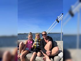 A joyful family enjoys a day on a pontoon boat, with kids smiling and having fun on the water — a perfect snapshot of family bonding and outdoor adventure.