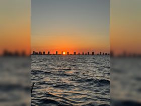 A stunning sunset over the skyline, viewed from the water, showcasing the tranquil beauty of the coastline.