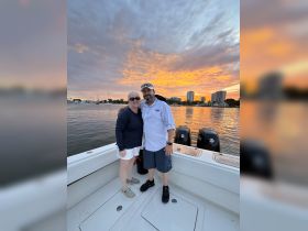 A couple enjoys a romantic moment on a boat at sunset, capturing the perfect backdrop for memorable celebrations on the water.