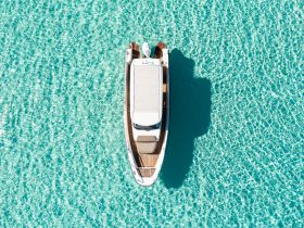 A stunning aerial view of a sleek boat gliding through crystal-clear turquoise waters, perfect for showcasing luxury boating experiences.