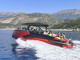 A lively group enjoys a thrilling ride on a speedboat, showcasing the excitement of on-water activities against a stunning mountainous backdrop.