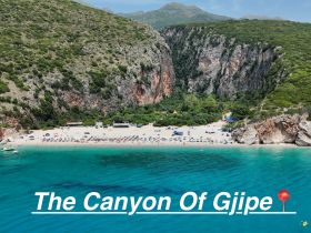 A stunning aerial view of the Canyon of Gjipe, showcasing a beautiful beach surrounded by lush cliffs — a perfect destination for sunbathing and water activities.