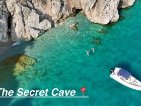A stunning aerial view of a couple swimming near a secret cave, with a boat anchored nearby in crystal-clear waters — an ideal spot for adventure and exploration.
