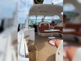 Interior view of a luxurious boat cabin featuring comfortable seating and a stylish table, perfect for relaxing or entertaining guests on the water.