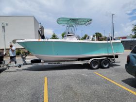 A vibrant speedboat is docked on a trailer, with a person nearby, showcasing its sleek design and ready for adventure.