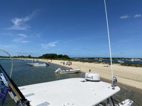 A scenic view of a beach with several boats anchored nearby, showcasing a perfect summer day for relaxation and fun on the water.