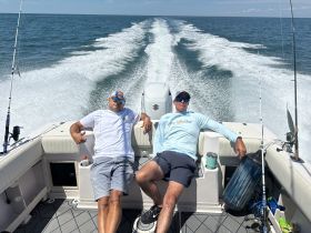Two friends relax on a fishing boat, enjoying the sun and the thrill of the open water — a perfect day for fishing and camaraderie.