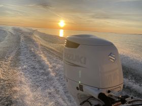 A stunning sunset view from the back of a boat, showcasing the Suzuki outboard motor as it cuts through the water, perfect for evening cruises.