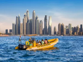 A vibrant yellow boat glides through the waters of Dubai, with a stunning cityscape in the background — perfect for sightseeing tours and exploring the iconic skyline.