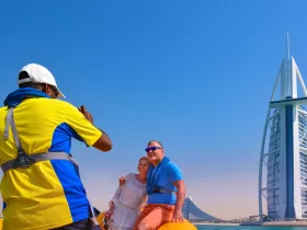 A couple poses for a photo with a stunning landmark in the background, capturing a memorable moment during their boating adventure.