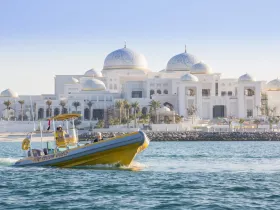 A vibrant yellow boat navigates the waters near a stunning architectural landmark, showcasing a perfect blend of adventure and scenic beauty.