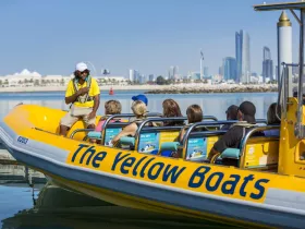 A guide engages a group on 'The Yellow Boats' tour, showcasing the stunning city skyline in the background — an exciting adventure on the water.