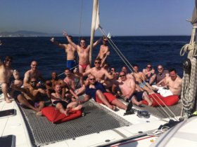A lively group of friends enjoys a fun day on a catamaran, celebrating with drinks and laughter under the sun — perfect for unforgettable party experiences on the water.