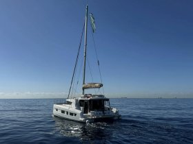 A stunning side view of a catamaran sailing smoothly on calm waters under a clear blue sky, perfect for exploring the open sea.