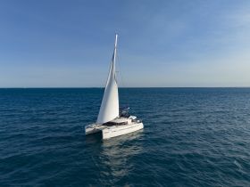 A stunning aerial view of a catamaran sailing through clear blue waters, perfect for showcasing the beauty of nautical adventures.