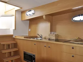 A well-designed boat interior featuring a modern kitchen area with wooden finishes and ample storage, perfect for preparing meals while at sea.