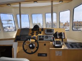 A well-equipped helm area showcasing the control console and steering wheel of a boat, perfect for navigating the waters.