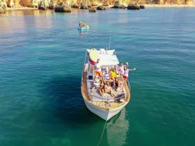 A lively group enjoys a boat party on the ocean, capturing the essence of fun and celebration in a stunning coastal setting.
