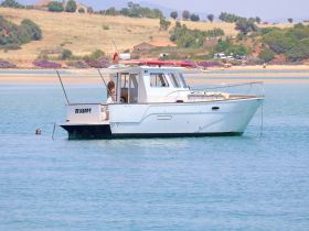 A serene moment featuring a boat named 'Be Happy' with a person swimming nearby, capturing the essence of relaxation and fun on the water.