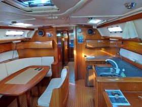 Interior view of a well-appointed boat cabin featuring comfortable seating and a functional kitchen area, perfect for relaxing and dining while on the water.