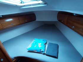Cozy cabin interior of a boat featuring a comfortable sleeping area with storage and decorative pillows, perfect for relaxing during a sailing trip.