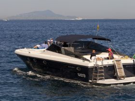A couple enjoys a relaxing moment on the deck of a sleek boat, surrounded by the serene ocean — perfect for a sunny day on the water.