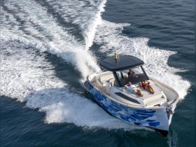 A couple relaxes on the deck of a stylish boat as it cruises through the water, showcasing the perfect blend of leisure and adventure on the open sea.