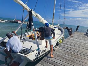 A lively group boards a sailboat at the dock, ready for an exciting day on the ocean. The vibrant atmosphere captures the anticipation of sailing adventures ahead.