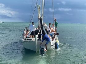 A lively group of guests enjoys their time aboard a boat near Caye Caulker, engaging in activities and soaking up the sun on the water.