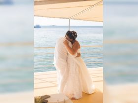 A couple shares a tender moment during their wedding ceremony on a boat, surrounded by serene waters — a perfect setting for a romantic celebration.
