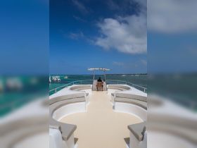 A serene view of the helm area on a boat, featuring comfortable seating and a captain at the controls, perfect for enjoying a day on the water.