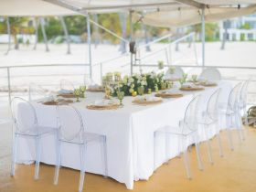 A beautifully set dining table on a boat, featuring elegant decor and clear chairs, perfect for hosting special events or intimate gatherings on the water.