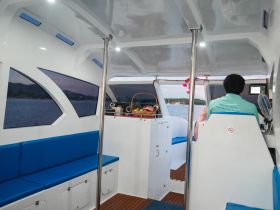 Interior view of a boat cabin featuring comfortable seating and a glimpse of the captain at the helm, perfect for relaxing during a scenic cruise.