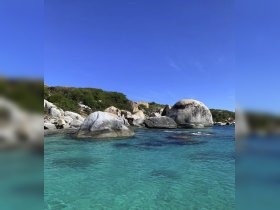 A stunning view of crystal-clear waters and unique rock formations along the coastline, perfect for showcasing the natural beauty of the destination.