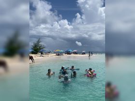 A lively group enjoys a fun day at the beach, swimming and sipping cocktails in the clear turquoise waters — perfect for a memorable beach party.