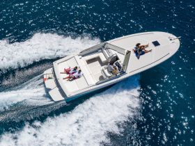 A couple enjoys sunbathing on the deck of a speedboat while cruising through sparkling blue waters — a perfect day for adventure on the sea.