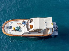 An aerial view of a couple relaxing on a stylish boat, enjoying the sun and clear blue waters — a perfect setting for a romantic getaway.