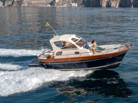 A couple enjoys a scenic ride on a stylish boat, capturing the essence of adventure on the water with stunning coastal views in the background.