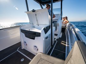 A stylish interior view of a yacht's helm and seating area, featuring guests enjoying the ride on the open water.