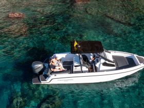 A couple enjoys a romantic moment on a sleek boat amidst crystal clear waters, perfect for unforgettable adventures on the sea.