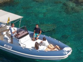 A lively group enjoys their time aboard a Joker boat, surrounded by crystal-clear waters, perfect for a fun day on the water.