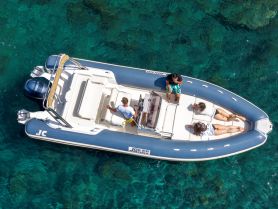 A group enjoys a sunny day on a boat, with two people sunbathing and another engaging with the captain — a perfect scene for summer fun on the water.