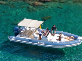 A group enjoys a sunny day on a boat, lounging on the deck while surrounded by crystal-clear waters — perfect for relaxation and fun on the water.