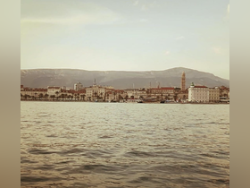 A picturesque view of the coastline and harbor, showcasing the beautiful architecture and mountains in the background — a perfect representation of a serene boating experience.