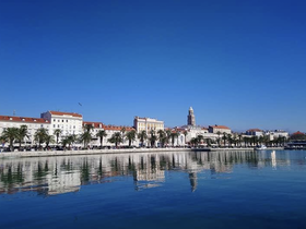 A picturesque view of a coastal town with palm trees and historic architecture reflected in the calm waters, perfect for showcasing beautiful destinations.