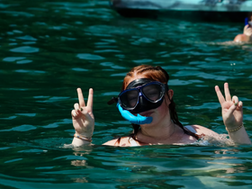 A snorkeler flashes a peace sign while enjoying the clear waters, capturing the essence of fun and adventure during a snorkeling trip.