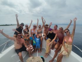 A lively group of friends and family enjoy a fun boat party, celebrating together on the water with smiles and waves.