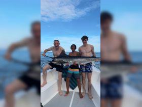 A group of friends proudly displays their impressive catch while enjoying a fishing trip on the water — a perfect moment of celebration and camaraderie.